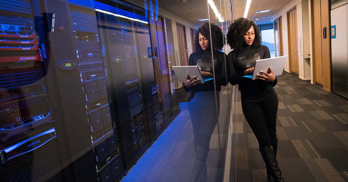 woman with laptop leaning on server